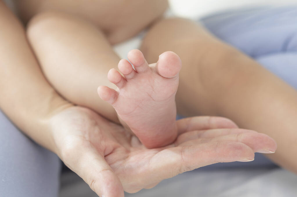 pies de bebé en manos de una madre joven  - Foto, imagen
