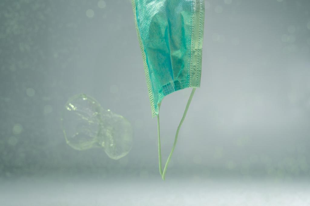 Plastikbecher und gebrauchte medizinische Maske im Wasser, ökologisches Konzept - Foto, Bild
