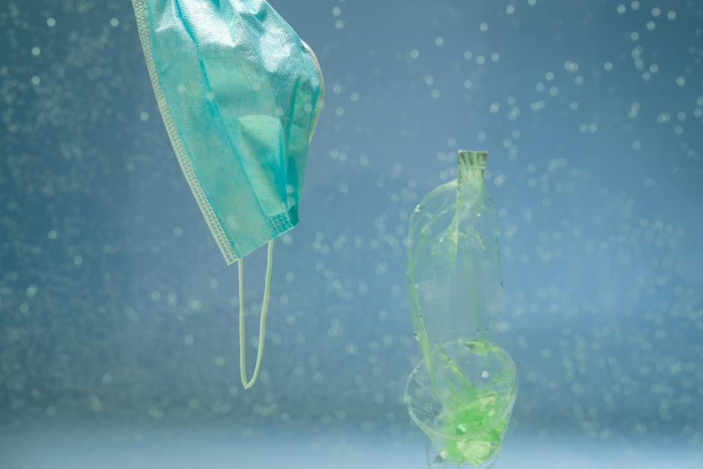 plastikowe śmieci w pobliżu zużytej maski ochronnej w wodzie, koncepcja ekologii - Zdjęcie, obraz
