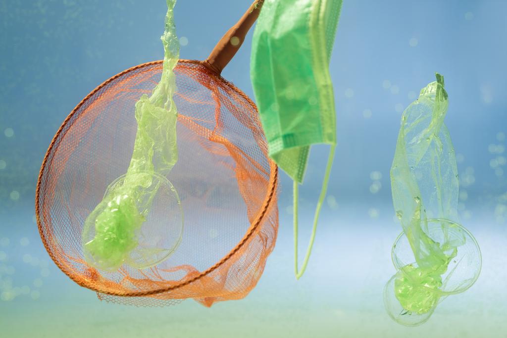 scoop-net près du masque médical et des sacs en plastique dans l'eau, concept écologique - Photo, image