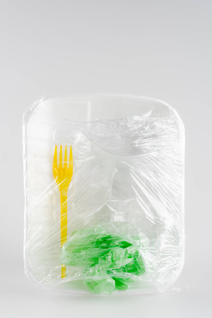 вид сверху пластиковой пластины, вилки и мешка упакованы в целлофан, экологическая концепция - Фото, изображение