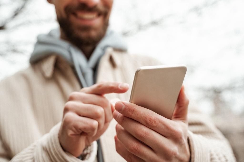 καλλιεργημένη άποψη του γενειοφόρου άνδρα δείχνοντας με το δάχτυλο στο smartphone  - Φωτογραφία, εικόνα