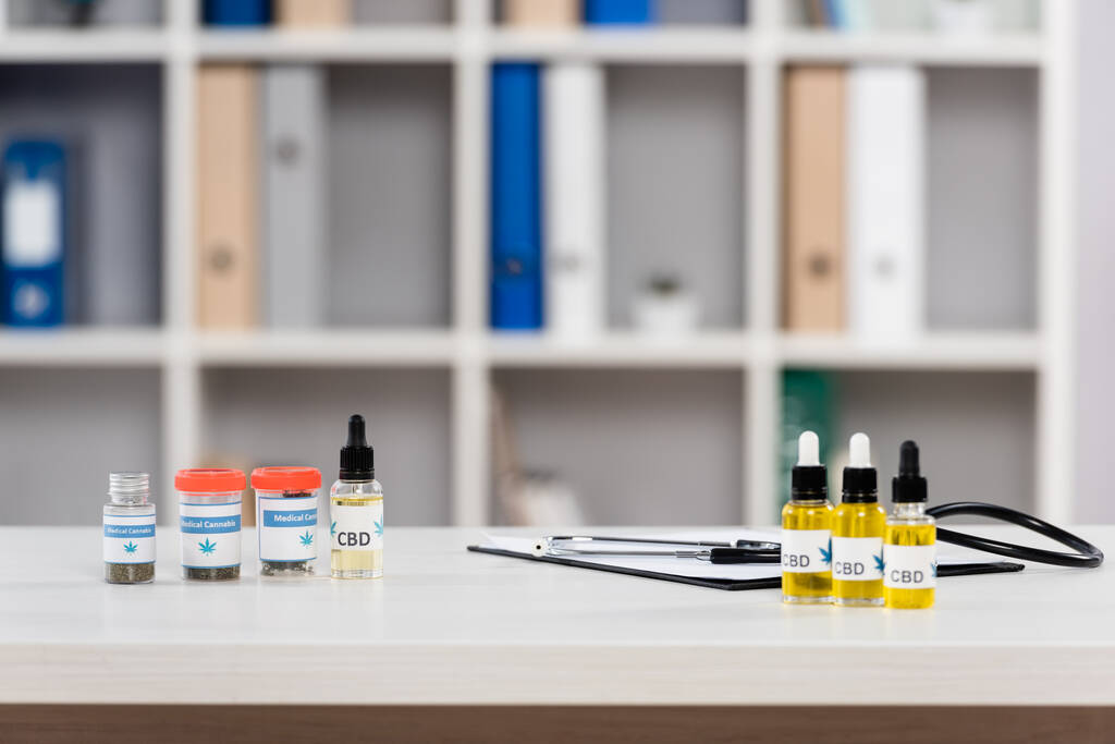 bottiglie con cannabis medica e scritte in cbd vicino agli appunti sulla scrivania in clinica - Foto, immagini