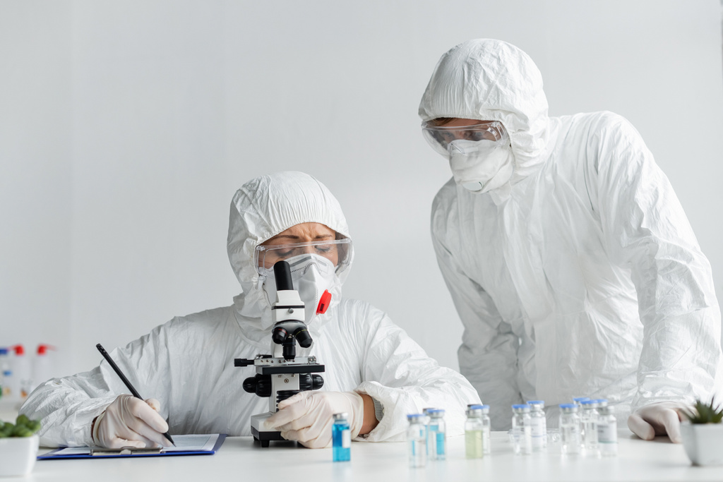 Wissenschaftler forschen an Impfstoff und schreiben im Labor auf Klemmbrett  - Foto, Bild