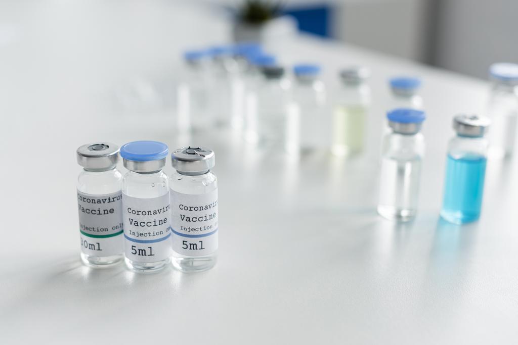Pots avec inscription du vaccin contre le coronavirus sur la table en laboratoire  - Photo, image
