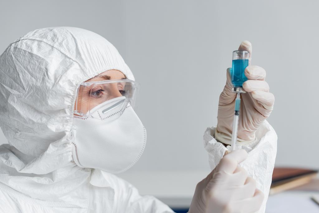 研究室で注射器でワクチンを拾う保護制服の科学者  - 写真・画像