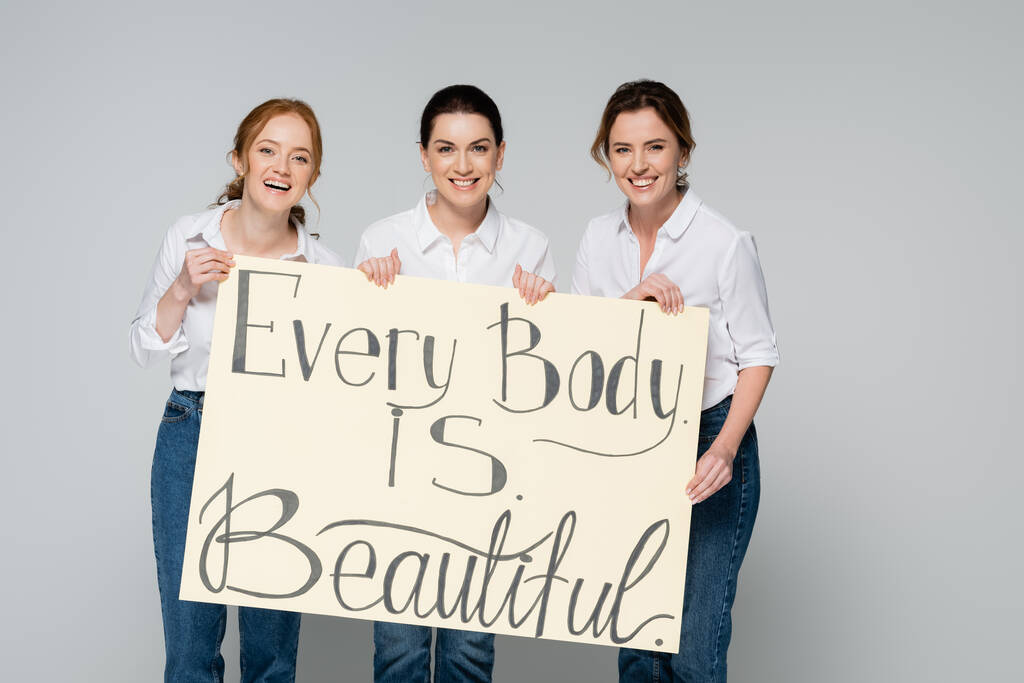 Iloinen naiset tilalla kyltti jokaisen kehon on kaunis kirjoitus eristetty harmaa  - Valokuva, kuva