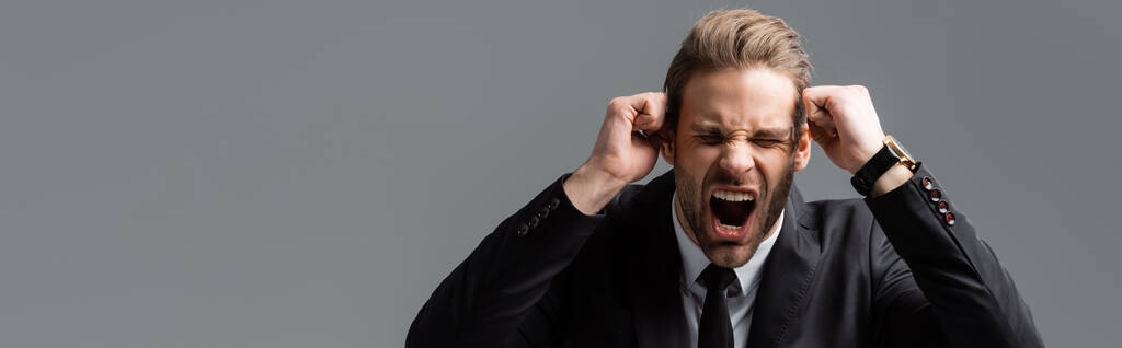 agresszív üzletember kiabál összeszorított öklökkel elszigetelt szürke, banner - Fotó, kép