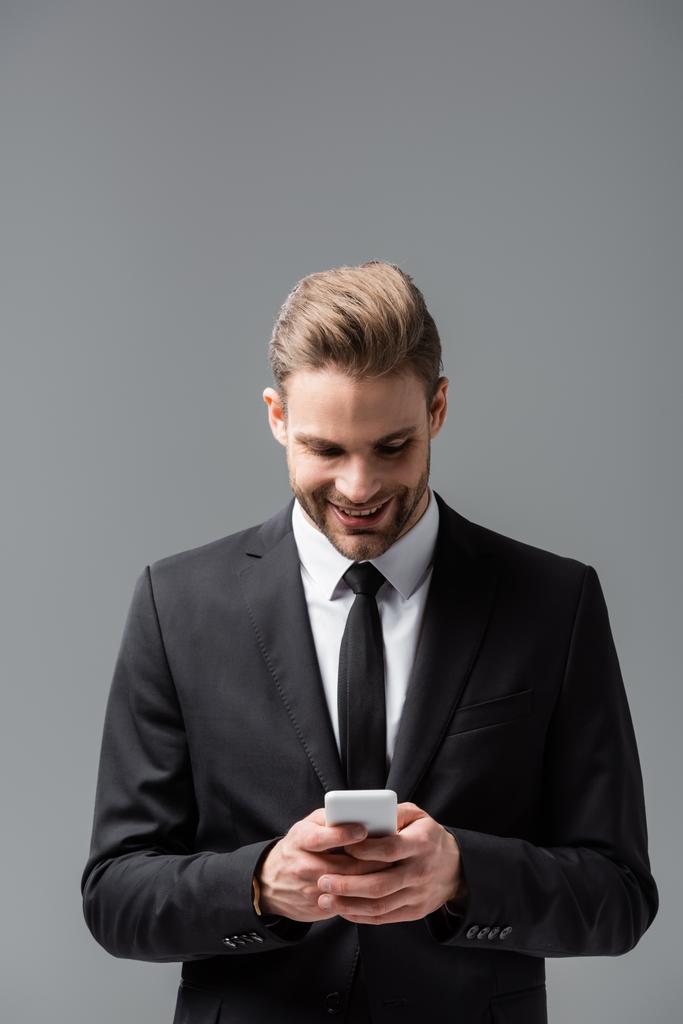 gestore sorridente messaggistica su smartphone isolato su grigio - Foto, immagini