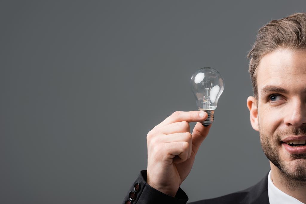 обрізаний вид позитивного бізнесмена, що тримає лампочку ізольовано на сірому
 - Фото, зображення