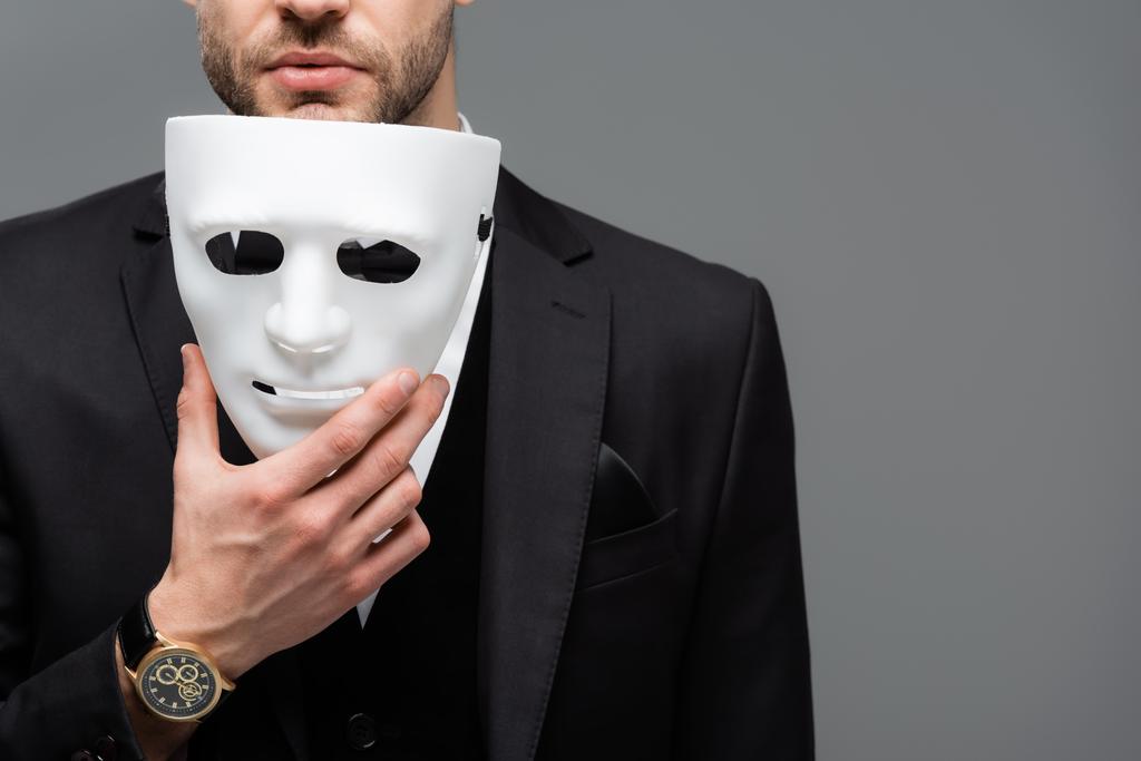 oříznutý pohled na obchodníka držícího masku izolovanou na šedi - Fotografie, Obrázek
