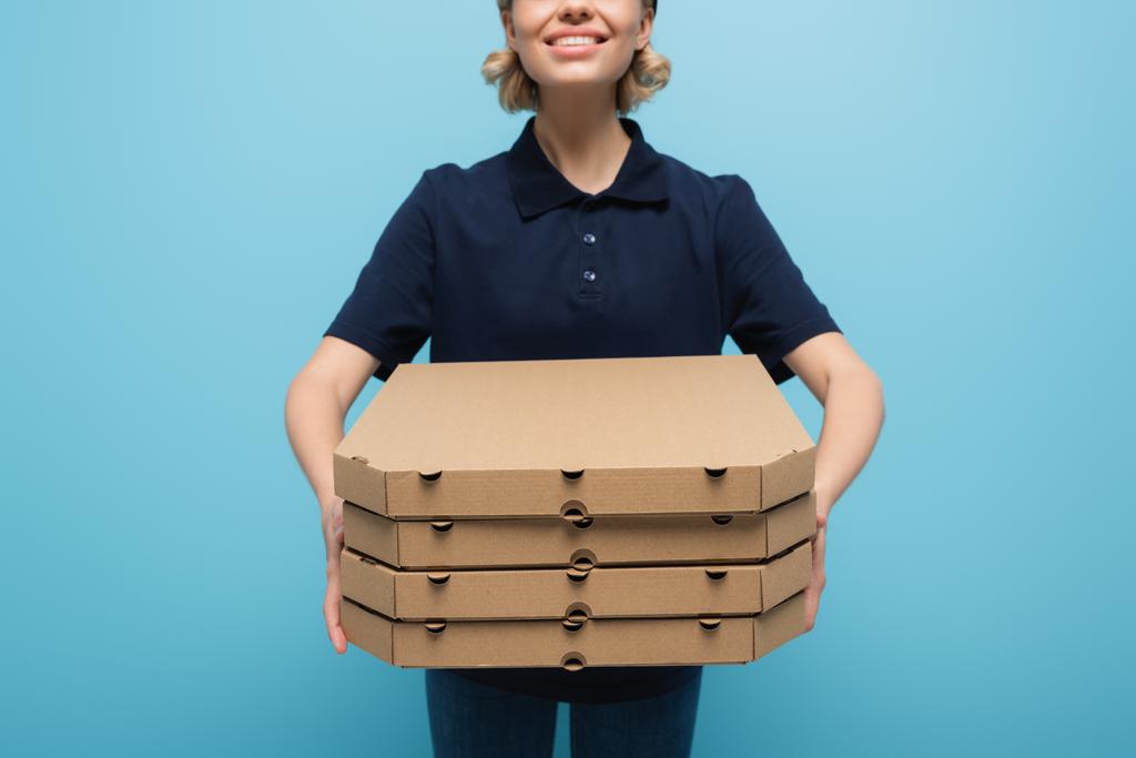 περικοπή άποψη του χαμογελαστού courier με κουτιά πίτσα απομονώνονται σε μπλε - Φωτογραφία, εικόνα