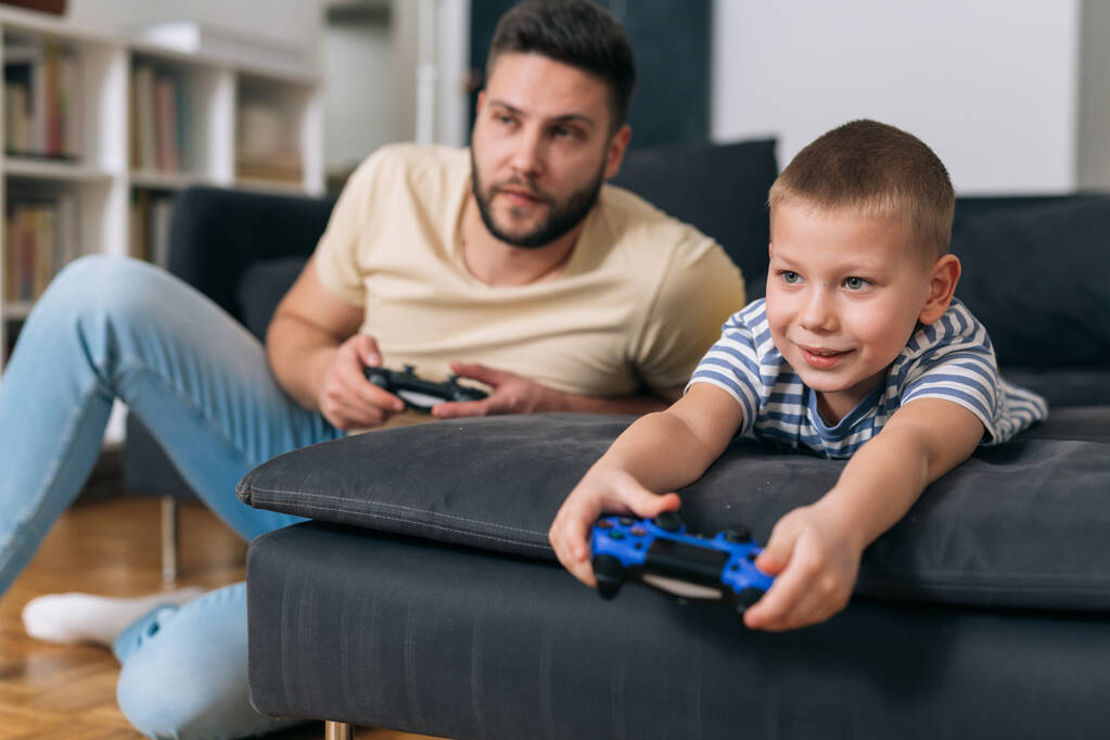 πατέρας και γιος παίζουν βιντεοπαιχνίδια στο σπίτι - Φωτογραφία, εικόνα