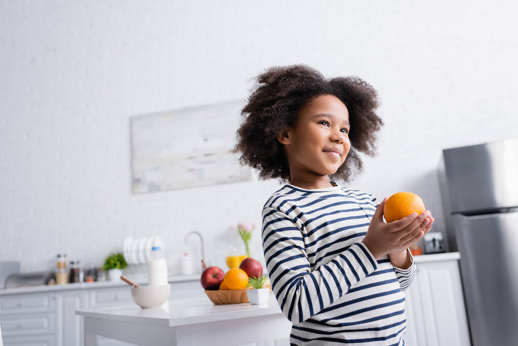 Afrikanische Amerikanerin mit frischer Orange in der Küche - Foto, Bild