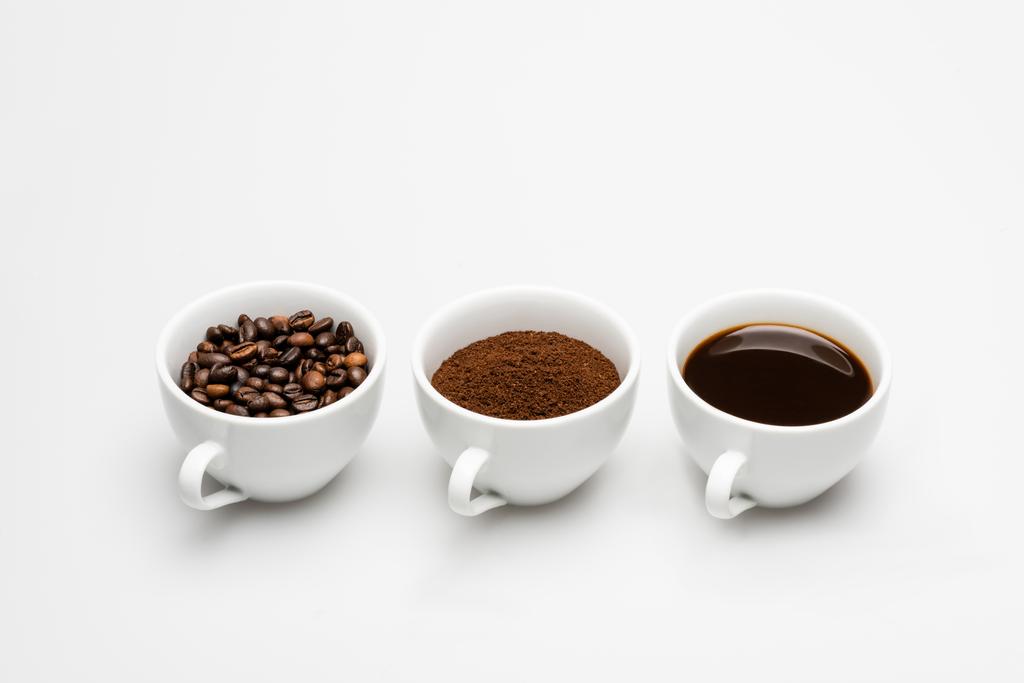 кружки с молотым и приготовленный кофе возле бобов на белом - Фото, изображение