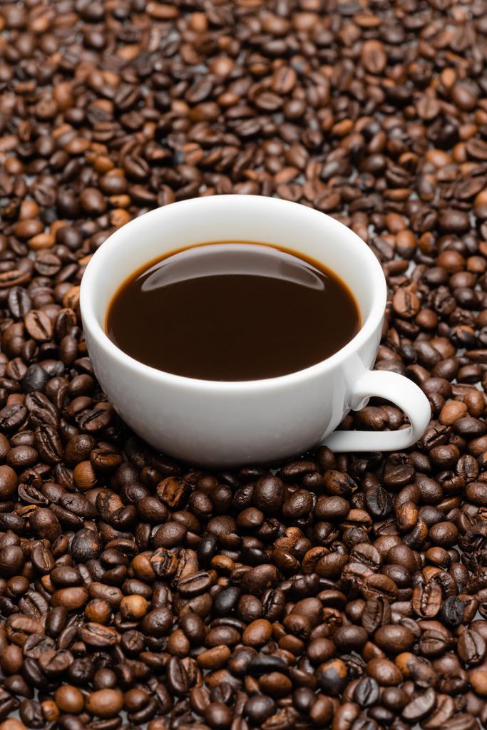 taza blanca con café preparado en granos marrones  - Foto, Imagen