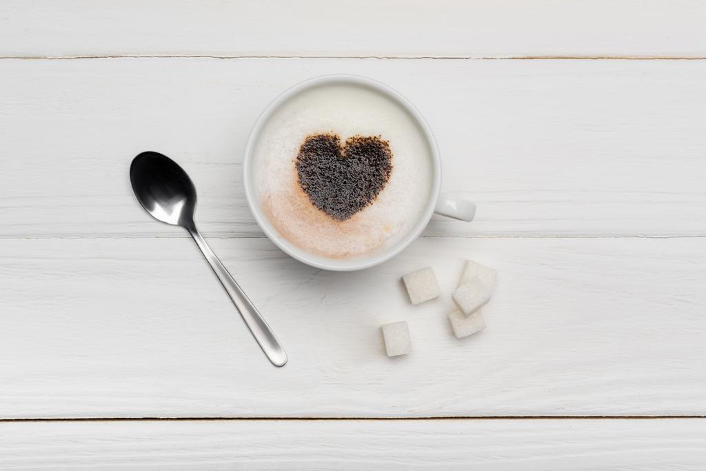 vista superior do copo com cappuccino perto da colher e cubos de açúcar no fundo de madeira branco   - Foto, Imagem