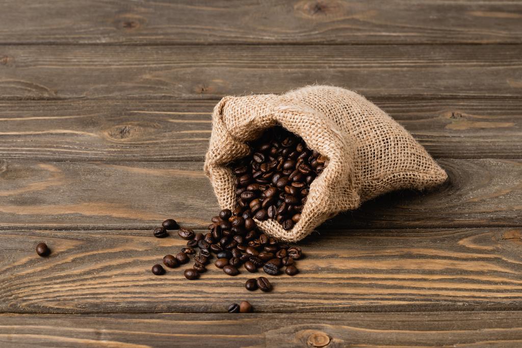 sac à dos avec grains de café torréfiés sur la surface en bois  - Photo, image