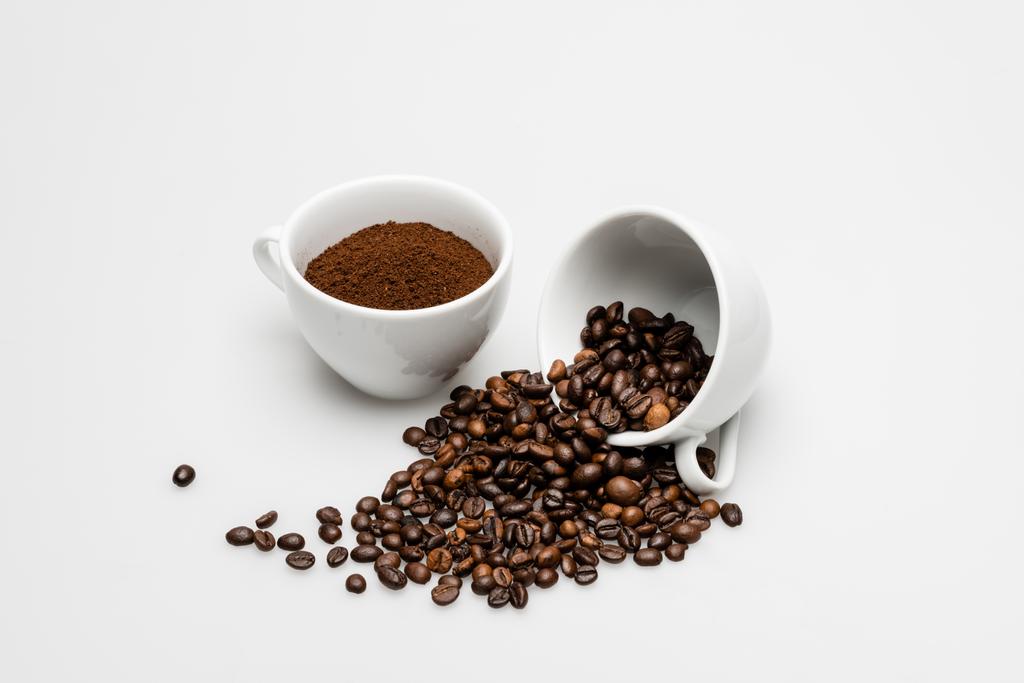 αλεσμένος καφές και ψητά φασόλια σε φλιτζάνια σε λευκό - Φωτογραφία, εικόνα