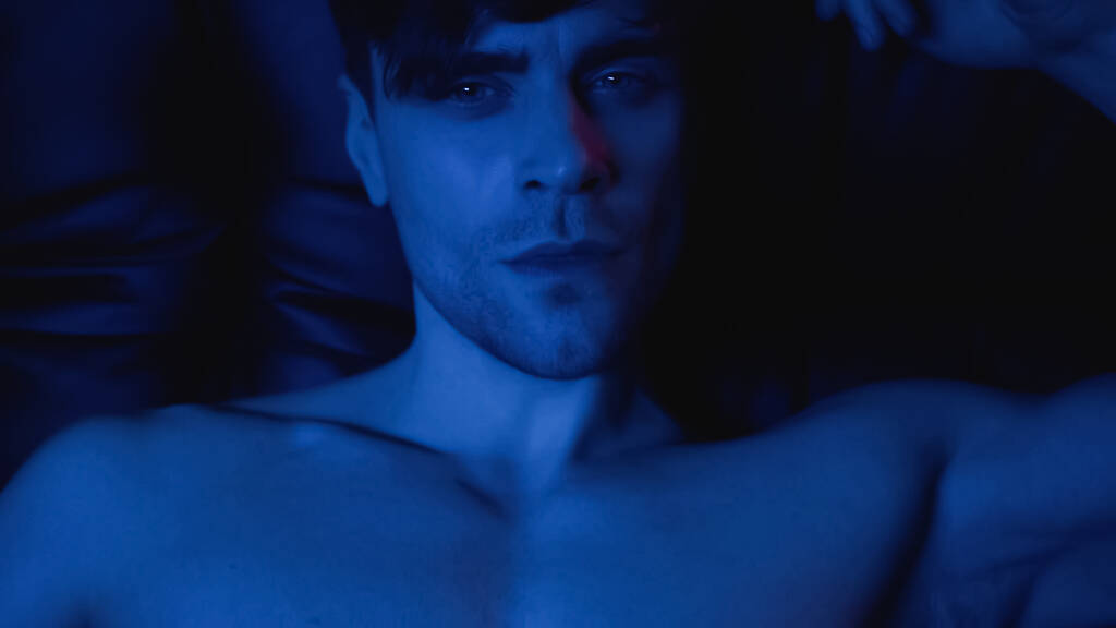 iluminación azul en el hombre sin camisa mirando a la cámara - Foto, Imagen