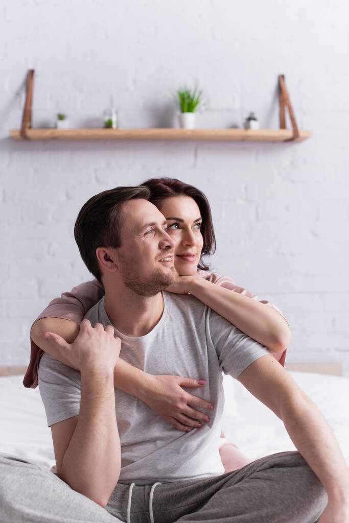 Felnőtt pár ölelkezik és félrenéz a hálószobában  - Fotó, kép