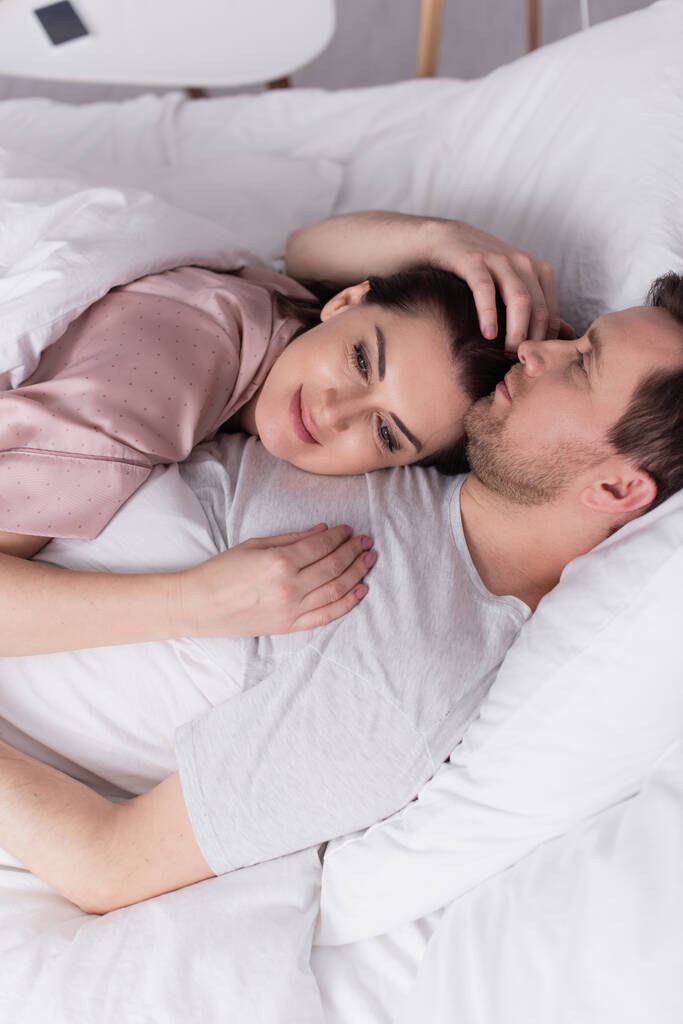 Aikuinen nainen makaa rinnassa miehensä sängyssä  - Valokuva, kuva