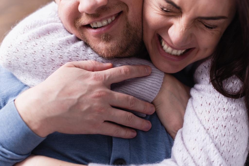 Χαρούμενη γυναίκα με πουλόβερ αγκαλιάζει γενειοφόρο σύζυγο  - Φωτογραφία, εικόνα