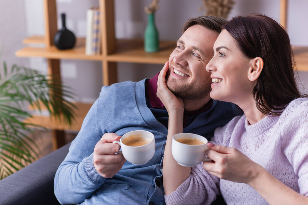 Mulher sorridente com xícara de café tocando marido  - Foto, Imagem