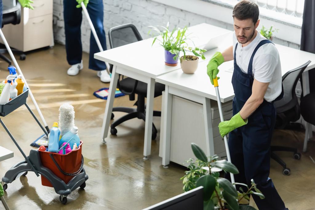 Reiniger in Gummihandschuhen wäscht Fußboden im Büro  - Foto, Bild