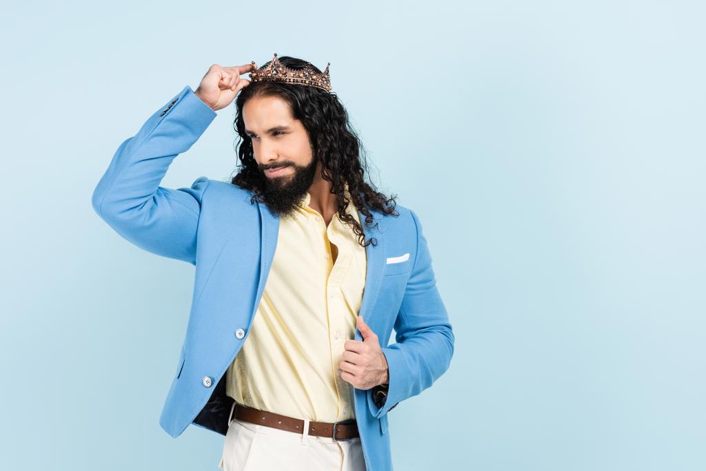 hombre hispano barbudo sonriendo y llevando corona aislada en azul - Foto, imagen
