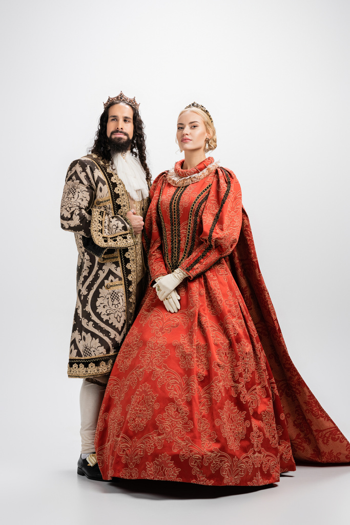 volle Länge des historischen gemischtrassigen Paares in Kronen und mittelalterlicher Kleidung auf weiß - Foto, Bild
