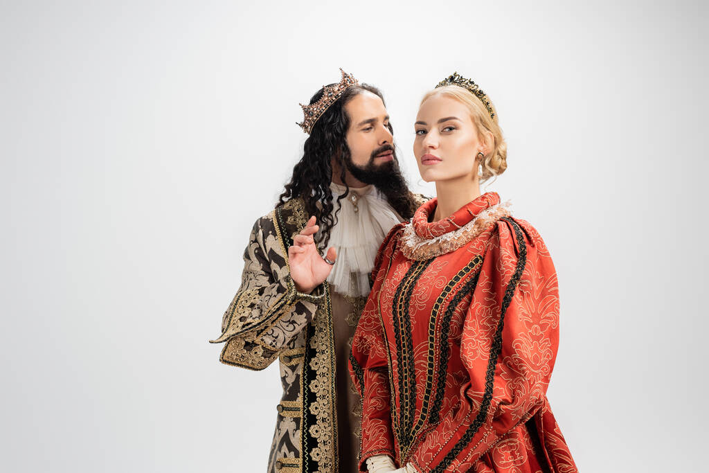 rey hispano en corona y ropa medieval mirando a la esposa rubia aislada en blanco - Foto, imagen