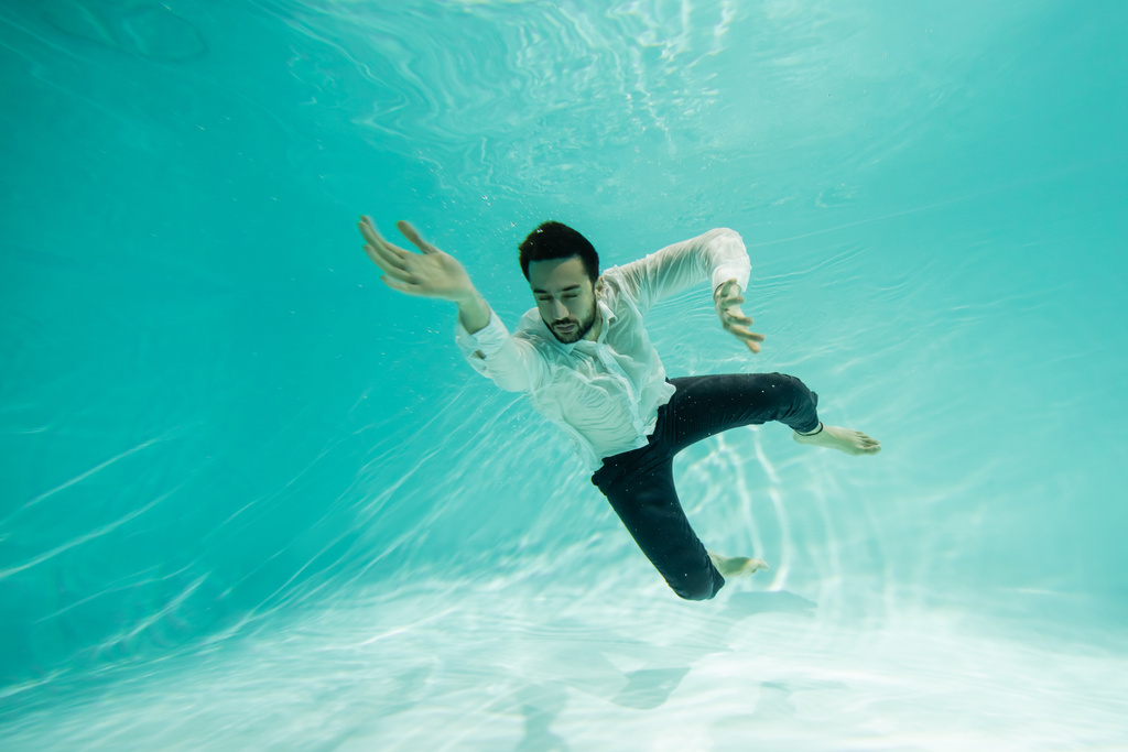 Молодий мусульманський бізнесмен з закритими очима плаває під водою в басейні
  - Фото, зображення