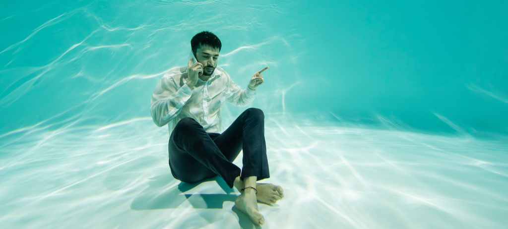 Homme d'affaires musulman pointant du doigt et parlant sur smartphone dans la piscine, bannière  - Photo, image