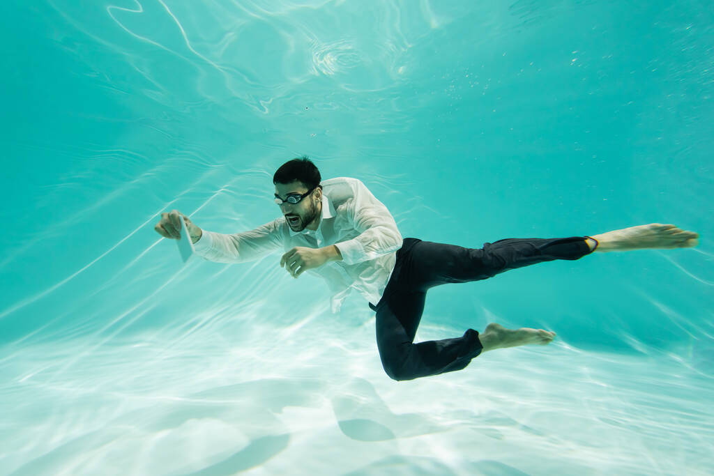 Muslimi liikemies suojalasit tilalla matkapuhelin vedenalainen uima-allas  - Valokuva, kuva