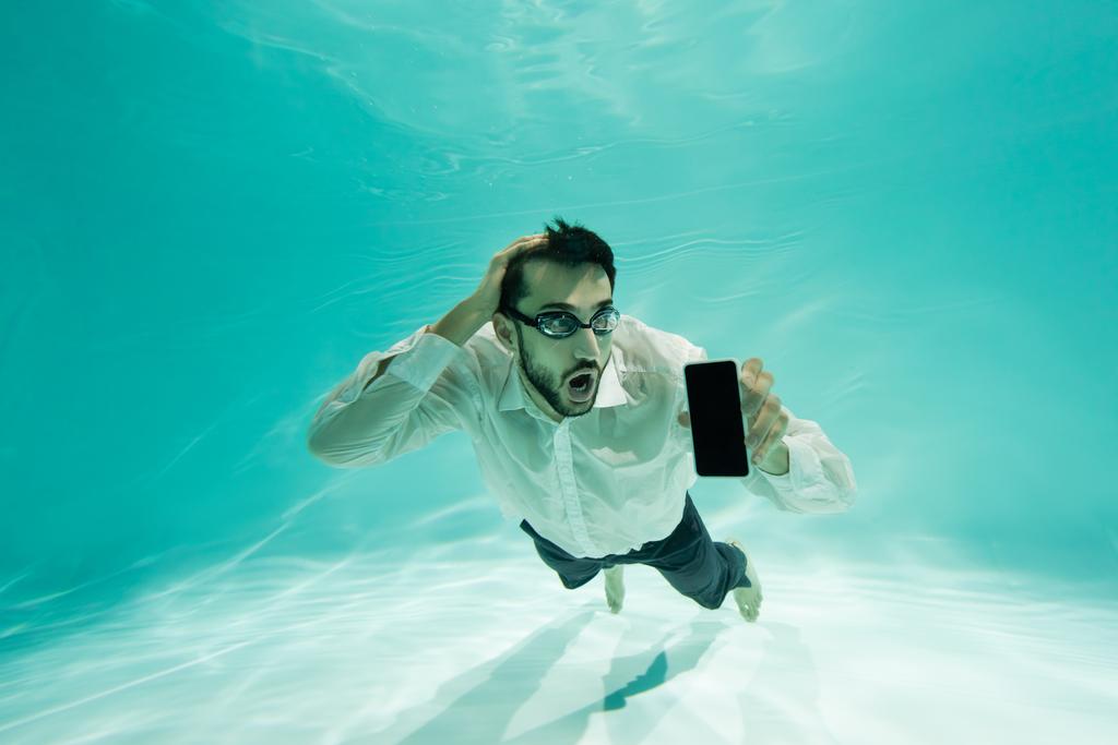 Удивительный арабский бизнесмен держит смартфон с чистым экраном под водой  - Фото, изображение