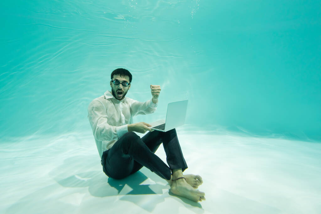 Захоплений мусульманський бізнесмен показує так жест і тримає ноутбук у басейні
  - Фото, зображення