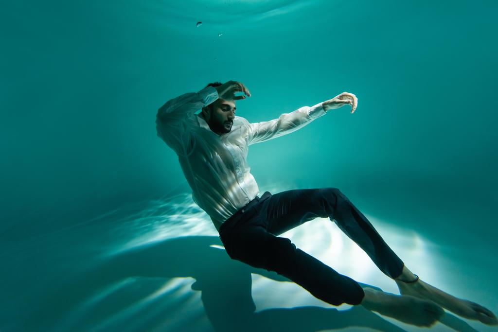 Arabischer Geschäftsmann schwimmt mit geschlossenen Augen in Pool  - Foto, Bild
