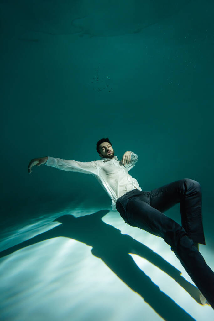 Arabische zakenman in wit overhemd zwemmen in zwembad  - Foto, afbeelding