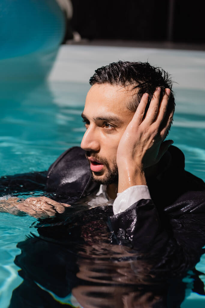Arabe homme d'affaires en combinaison humide regardant loin dans la piscine  - Photo, image