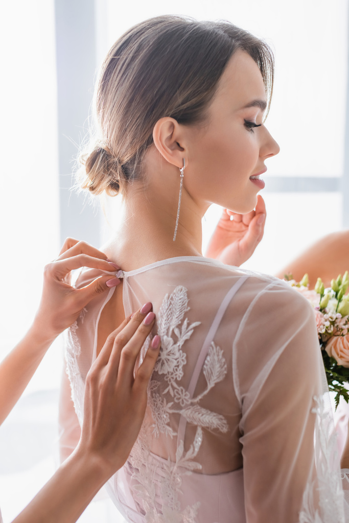 Brautjungfer knöpft Spitzenkleid auf hübscher Braut - Foto, Bild