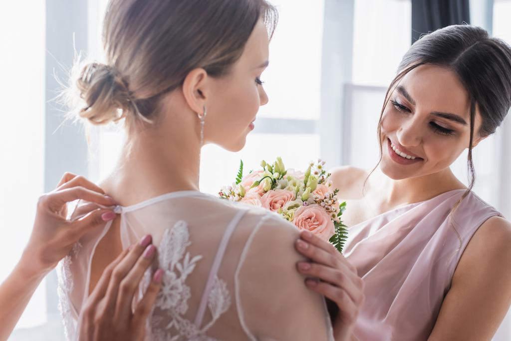 Brautjungfern bereiten junge Frau auf Hochzeit zu Hause vor - Foto, Bild