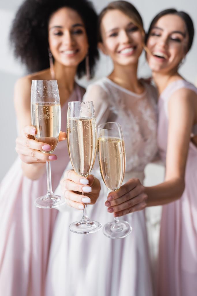 šťastná nevěsta s různými družičky drží sklenice šampaňského na rozmazaném pozadí - Fotografie, Obrázek