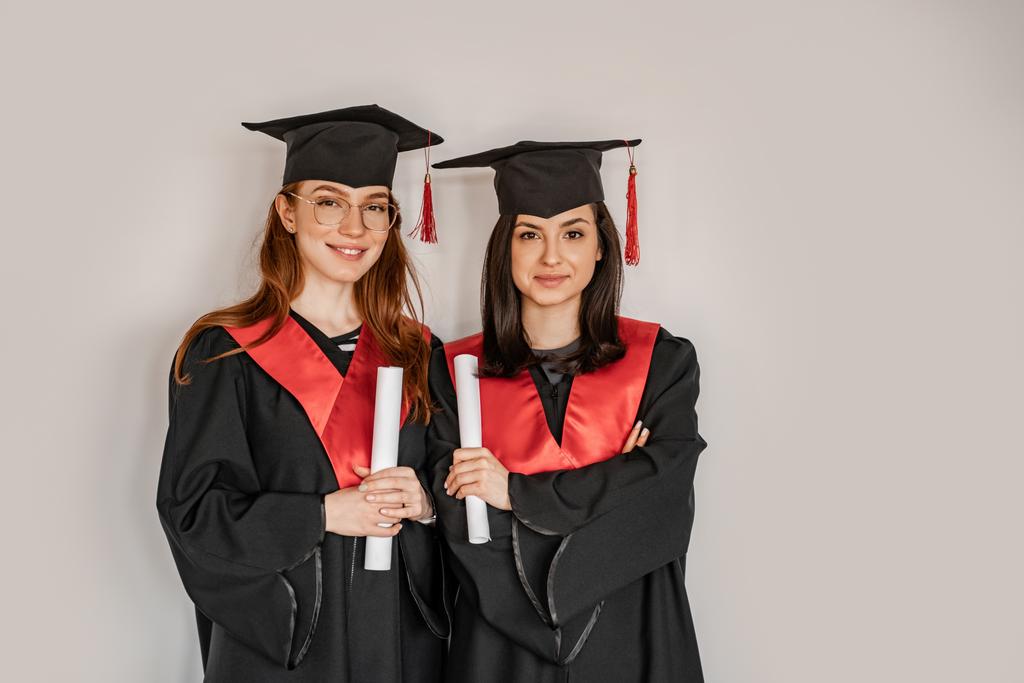 jolis étudiants en robes et casquettes de fin d'études titulaires d'un diplôme en rouleaux de papier, senior 2021 - Photo, image