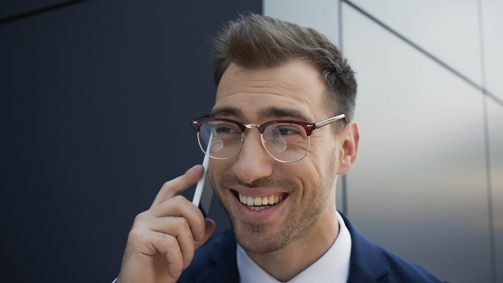 cheerful businessman in glasses talking on mobile phone near building  - Photo, Image