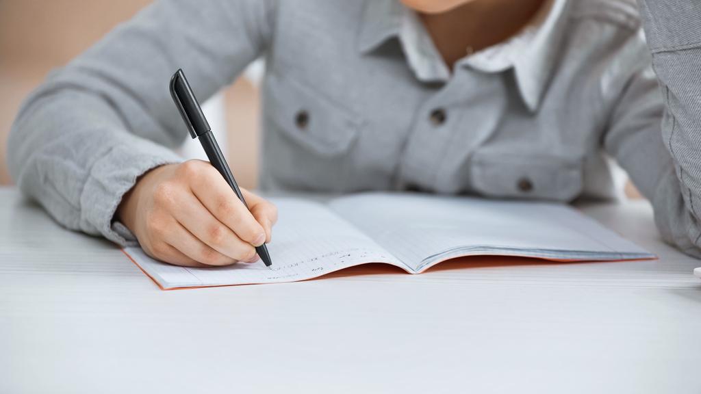 Vista recortada de niño escribiendo en el cuaderno en la mesa  - Foto, imagen