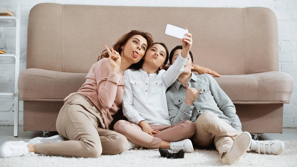 KYIV, UKRAINE -  APRIL 15, 2019: Family taking selfie near joystick on floor  - Foto, afbeelding