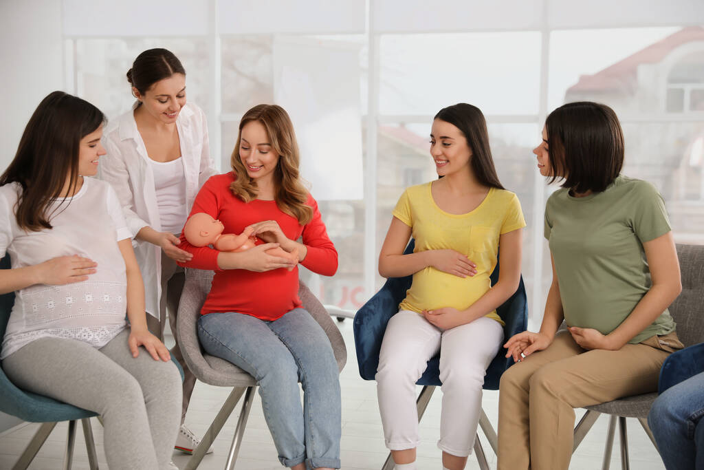 Groep zwangere vrouwen met vroedvrouw op cursussen voor aanstaande moeders binnen - Foto, afbeelding
