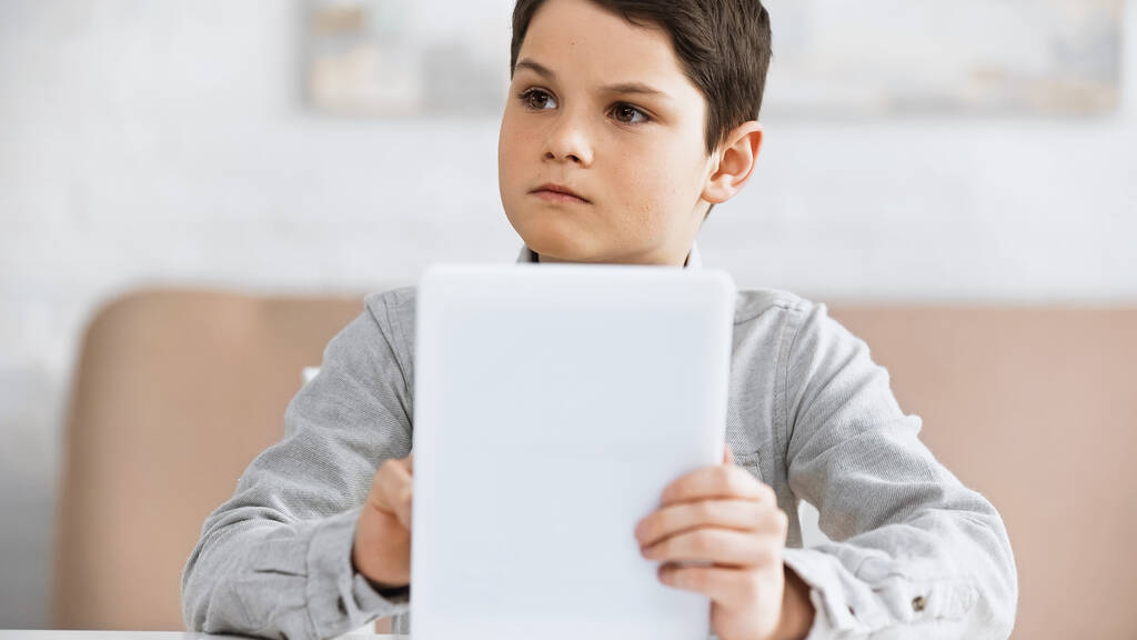 Nastolatek trzymający cyfrową tabletkę na niewyraźnym pierwszym planie podczas edukacji online  - Zdjęcie, obraz