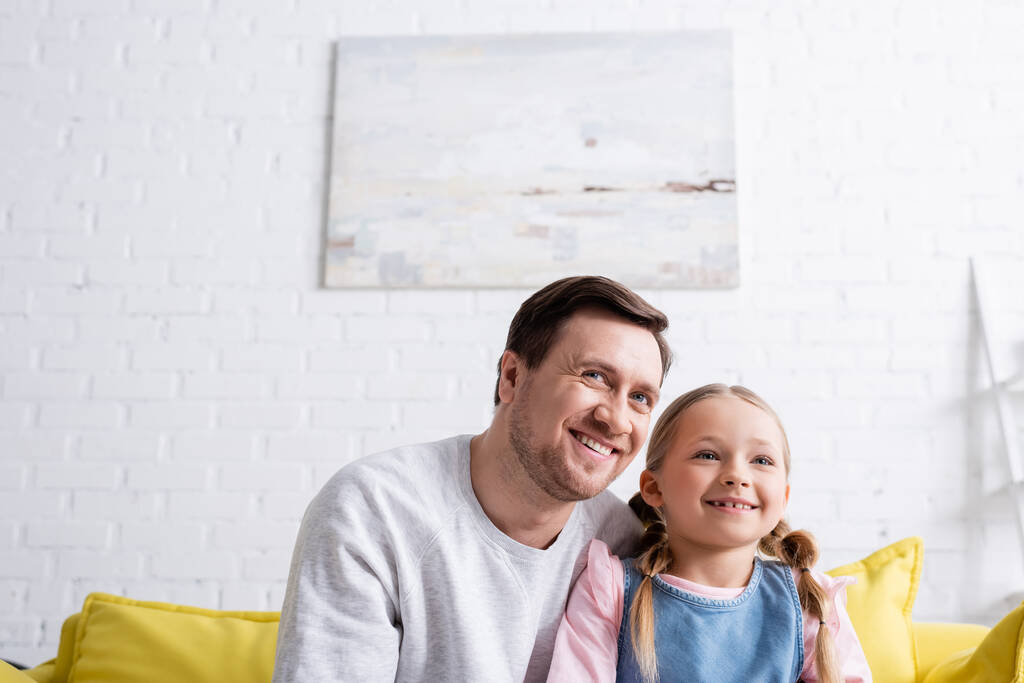 веселый отец и дочь, глядя в сторону и улыбаясь дома - Фото, изображение